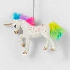 a white unicorn ornament with multicolored hair on it's tail