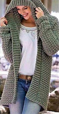 a woman wearing a green knitted cardigan and jeans, with her hands on her hips