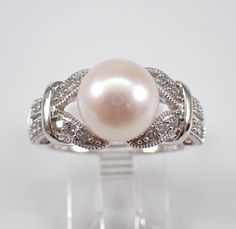 a white pearl and diamond ring on display