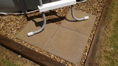 a metal object sitting on top of a cement slab next to grass and gravel covered ground