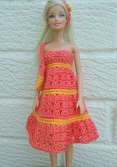 a doll wearing a crocheted dress and headband standing in front of a white brick wall