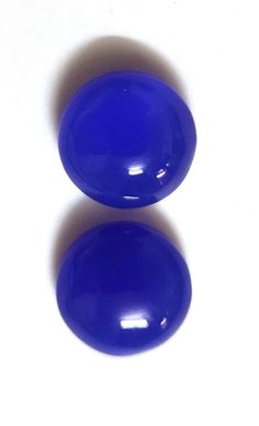 two blue eggs sitting next to each other on a white surface