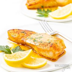 two white plates topped with fish and lemon slices