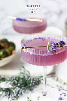 a pink cocktail with lavender garnish on the rim