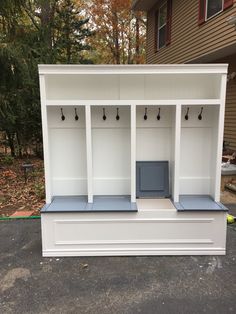 a white bench with three benches and two coats hanging on it's sides in front of a house