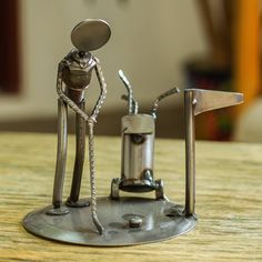 a metal figurine standing next to a coffee grinder on top of a wooden table