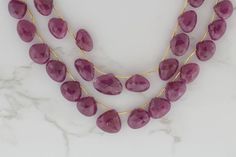 three strand necklace with purple stones on marble surface