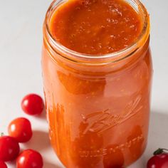 a jar filled with tomato sauce next to some tomatoes