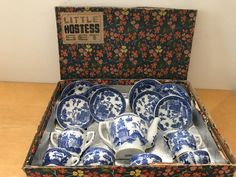 a box filled with lots of blue and white china cups sitting on top of a wooden table