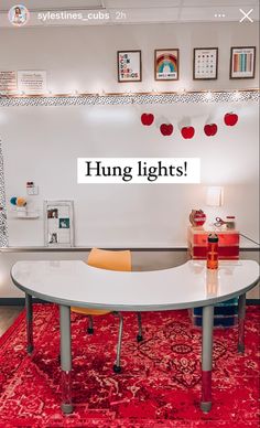 a white table sitting on top of a red rug next to a wall filled with pictures