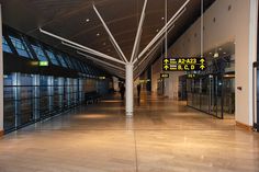 an empty airport terminal with glass doors and signs hanging from the ceiling in front of them