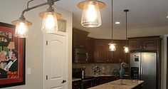 a kitchen with an island and lights hanging from the ceiling