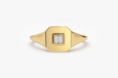 a gold signet ring with a baguette cut diamond set in the center