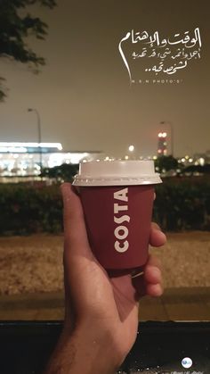 a hand holding a coffee cup in front of a cityscape with the words cota written on it