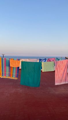 colorful towels hanging out to dry on a clothesline over looking the ocean, against a blue sky