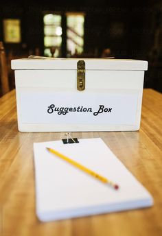 a wooden table topped with a white box filled with writing and a pencil next to it