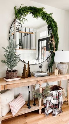 a wooden table with christmas decorations on top and a mirror in the corner above it