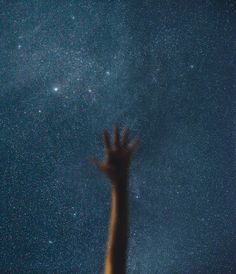 a person reaching up into the sky with their hands in the air and stars above them