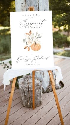 an easel with a sign on it that says welcome to the engagement party and pumpkins