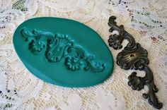 a green cookie mold sitting on top of a lace covered tablecloth next to an ornate cast iron door handle