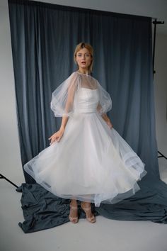 a woman in a white dress and veil posing for a photo with her hands on her hips