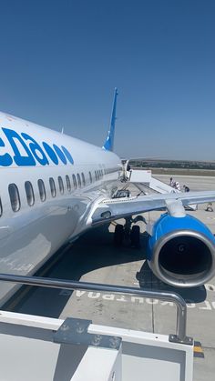 an airplane is parked on the tarmac with its door open and people standing around it