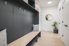 a black and white entryway with wooden bench next to potted plant on the wall