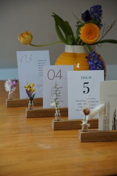 the table is set up with place cards and flowers in vases on each side