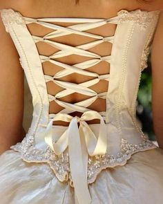 the back of a woman's dress with white ribbons and laces on it