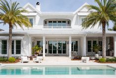 a large white house with a pool and palm trees