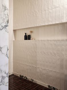 a bathroom with marble walls and flooring next to a white tiled shower stall area