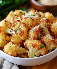 a white bowl filled with cauliflower covered in parmesan cheese