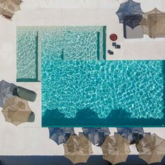 an aerial view of a pool with umbrellas and chairs