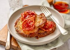 two pieces of bread with meat and tomato sauce on them, sitting on a plate