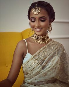 a woman wearing a white sari and gold jewelry