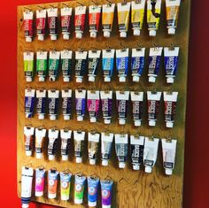 a wall mounted shelf with many different types of toothpaste on it and hanging from hooks