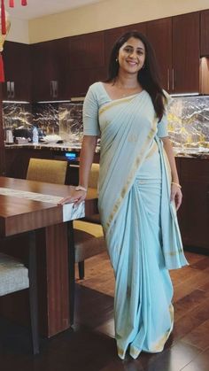 a woman in a blue sari standing next to a table