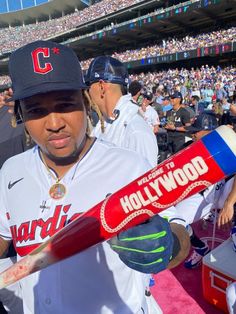 a baseball player holding a bat in front of a large crowd at a ball game