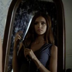 a woman standing in front of a mirror brushing her hair