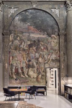 a large painting on the side of a wall in a room with chairs and tables