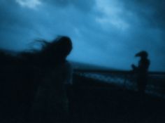 a blurry image of two people standing in the dark with their hair blowing in the wind