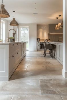 an open kitchen and dining room area with large tile flooring, white cabinets and gray countertops