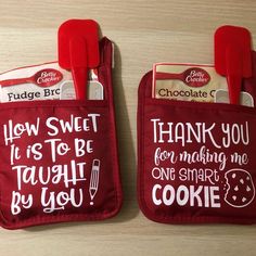 two red oven mitts with funny sayings on them, one has a cookie in it and the other says how sweet it is to be taught by cookies