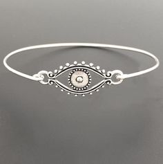 Evil Eye Bracelet - Evil Eye JewelryA detailed silver tone evil eye charm will be transformed into a beautiful evil eye bracelet with bangle band choice of silver filled or sterling silver.Also available with a gold tone evil eye and bangle band choice of brass or 14k gold filled band. If you want this option for your evil eye bracelet bangle, select from options when ordering.This evil eye bracelet looks great stacked with other bangles from my collection as you can see from the last 4th pictur Adjustable Silver Evil Eye Bracelet, Adjustable Silver Round Evil Eye Bracelet, Adjustable Metal Evil Eye Jewelry, Metal Evil Eye Bracelet, Silver Bohemian Evil Eye Bracelet, Bohemian Evil Eye Metal Jewelry, Adjustable Metal Evil Eye Bracelet, Metal Charm Bracelet With Evil Eye, Adjustable Silver Bohemian Evil Eye Bracelet