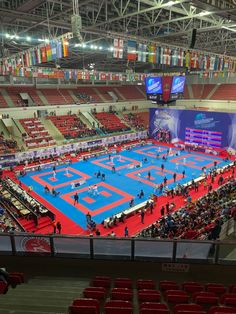 an indoor arena with red seats and blue flooring is seen from the upper level