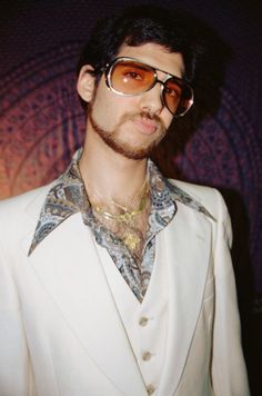 a man in a white suit and sunglasses