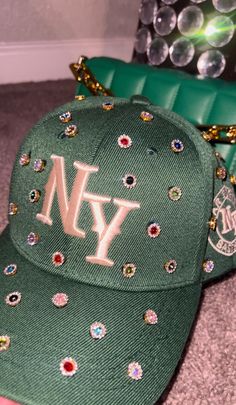 Adjustable NY Custom Bedazzled Hat customed by ShanayCosmetics Comes in 2 colors: Black or Green More colors COMING SOON....  PLEASE KEEP IN MIND THAT I AM NOT RESPONSIBLE FOR ANY DELAYS WITH SHIPPING ONCE I HAVE DROPPED YOUR PACKAGE OFF AT THE POST OFFICE! THAT IS OUT OF MY CONTROL. PLEASE BE AWARE I AM NOT RESPONSIBLE FOR ANY LOST, DAMAGED OR STOLEN PACKAGES!! Custom Ny Hat, Bedazzled Clothing, Diy Leather Hat, Bedazzled Hat, Custom New Era Hats, Customized Hats, Bedazzled Stuff, Swag Items, Rhinestone Hat