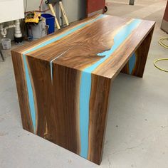 a table made out of wood with blue strips on the top and bottom, sitting in a garage