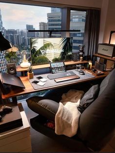 a desk with a laptop, monitor and keyboard on it in front of a window