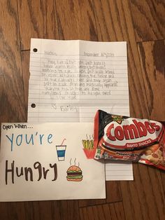 a note and candy bar are sitting on the table next to some writing paper that says, you're hungry